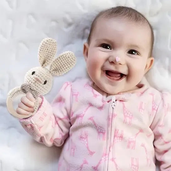 Bébé riant avec un jouet lapin fait main.