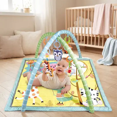 Bébé sur le ventre s'éveillant sur son tapis d'éveil avec arche rembourré