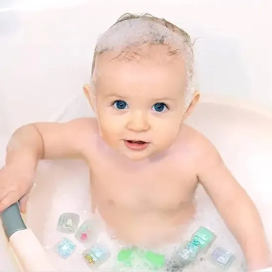 Enfant joue avec cubes flottants colorés dans baignoire.