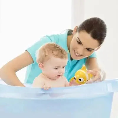 Bébé intrigué par poisson flottant dans la baignoire bleue