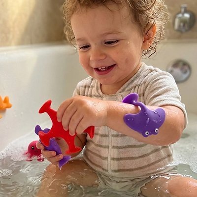 Enfant joue joyeusement avec jouets aquatiques colorés dans baignoire