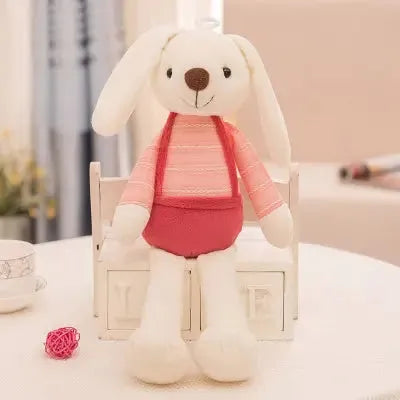Jouet textile lapin habillé en rose sur table blanche