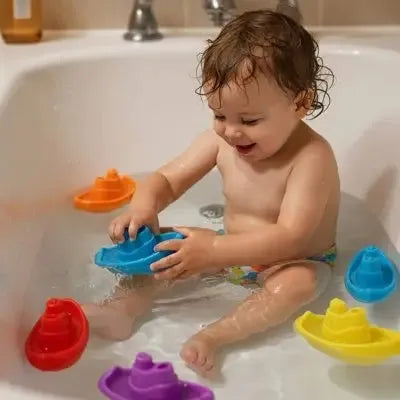 Enfant s'amusant avec bateaux flottants colorés dans la baignoire