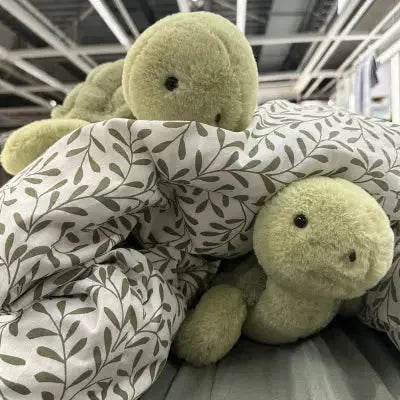 Compagnon en peluche tortue vert sous couverture feuillue