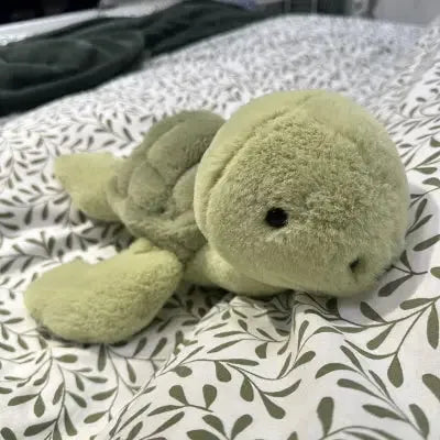 Compagnon tortue en peluche sur drap feuillu blanc