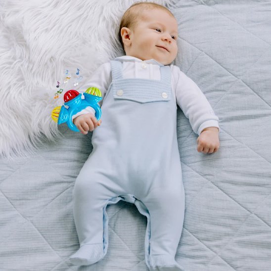 Hochet bébé musical couché sur le lit sourire en coin 