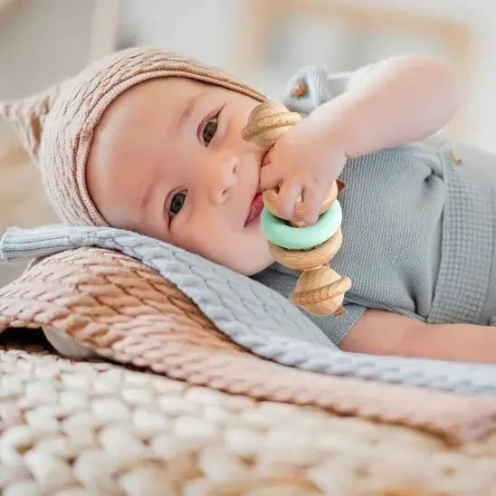 Bébé joyeux mordillant un jouet naturel aux teintes douces
