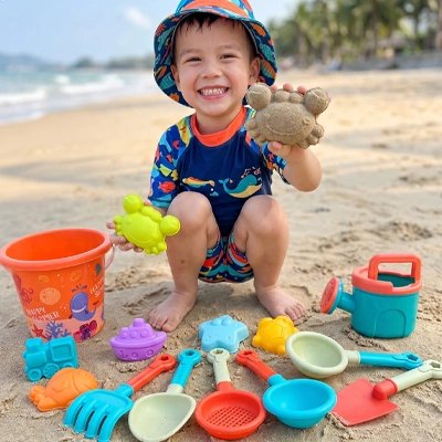 jeune garçon s'amuse avec jouets d'été sur la plage
