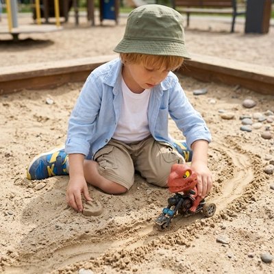 Enfant jouant avec figurine préhistorique dans bac à sable