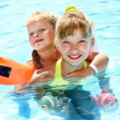 Enfants joyeux jouant avec poissons flottants en piscine.