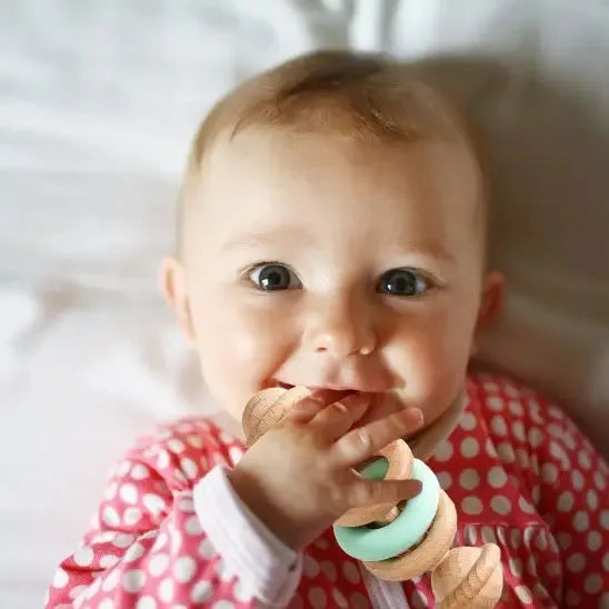 Bébé souriant explorant un jouet naturel en bois coloré