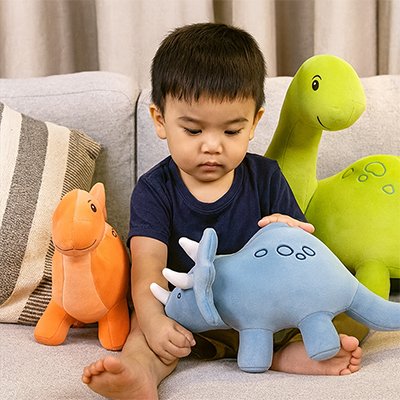 Peluche dinosaure les trois couleurs avec jeune garçon