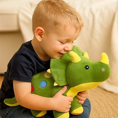 Peluche dinosaure vert dans les bras d'un petit garçon