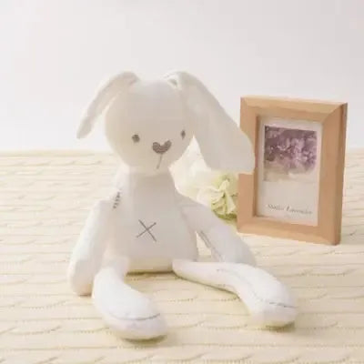 peluche lapin blanc assis sur une surface beige