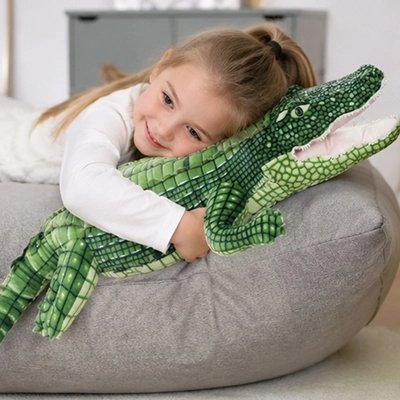 peluche pour enfant reptilien enlacé autour des gras d'une fillette
