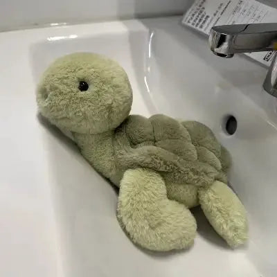 Peluchée tortue verte reposant dans un lavabo blanc